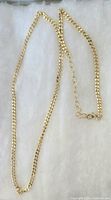 Image shows a gold plated box chain necklace laid out on a soft white surface, chain has small square links and a 2 inch extender with clasp for adjustable length.