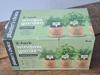 Front view of Planter's Choice 9-Herb Window Garden 31-piece kit box showing images of potted herbs and list of included items.