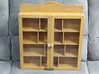 Front view of wood display case showing two glass doors and wooden compartments inside.