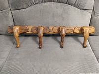 Full view of the wood hanging rack showing four elephant head shaped hooks mounted on a rectangular wooden base, displayed on a gray fabric surface.