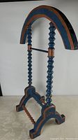 Side view of the vintage blue and orange wooden Masonic candle holder with carved spindle posts and arched top.