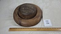 Top and side view of the rounded wooden hat mold showing the dome shape and natural wood grain with cracks.