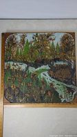 Full view of framed 21x21 inch folky style wilderness painting showing trees, river, wildlife including moose, and cabin.