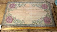 Full view of rectangular hooked rug showing entire design with pastel roses and flowers bordered in grey.
