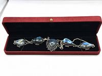 Labradorite necklace laid inside a red velvet box with black interior lining, showing all five teardrop stones connected by silver settings and a silver chain.