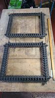 Two rectangular thorn wood tramp art frames laid flat on a wooden surface with a measuring stick to show size.