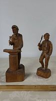 Two wooden folk art carvings, one a blacksmith 10 inches tall signed Caron, the other a man holding a cleaver 8 inches tall.