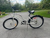 Side view of the white Super Cycle Pedro step-through bike showing frame, tires, fenders, seat, and kickstand.