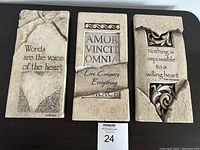 Three stone wall hangings placed side by side, showing quotes and textured stone design.
