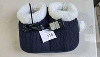 Blue knitted fabric foot massager with white plush lining and attached power cord and adapter, shown from top.