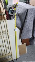 Full view of the yellow extendable pole with grabbers, showing length and construction.