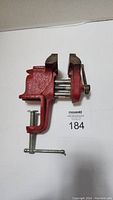 Red portable table vise shown from the top and clamp side to display jaws and mounting clamp fully visible.