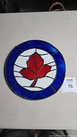 Top-down photo of stained glass RCAF roundel with red maple leaf and blue ring on white background.