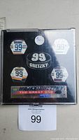Front view of collectible pin set in clear plastic case showing five Wayne Gretzky jersey and number 99 pins plus black oval pin with '99 Gretzky'