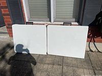 Two folded tables leaning against brick exterior