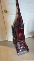 Front view of the maroon Bissell ProHeat Pet Carpet Cleaner with visible brand and model logos and clear pet tool on front.