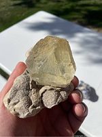 Front view of pale yellow-green fluorite cubic crystal on white-beige matrix, hand-held