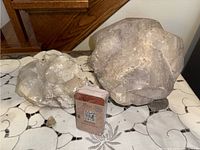 Two large clear quartz crystal formations with a small deck of mineral identification cards on a patterned fabric surface.