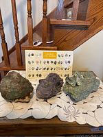Three large rough mineral specimens displayed in front of 'Minerals of Canada' identification board.