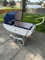 Photo of vintage Rex Stroll-O baby pram in blue and white on paved backyard patio showing side and wheels.