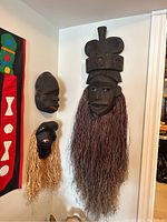 Photo showing all three masks together hung on a wall, illustrating size differences and diverse styles.