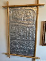 Full straight-on view of the three-section embossed metal panel framed with bamboo