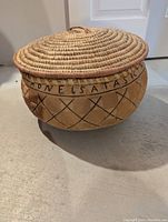 Photo of vintage round basket with woven lid, carved wood base with geometric patterns and letters.
