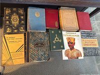 Two-row overview of ten hardcover books on a shelf, various bindings and dust jackets visible.