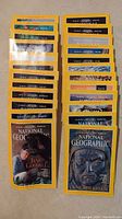 Top down view of two stacks of National Geographic magazines with yellow borders. Front covers feature Jane Goodall and Genghis Khan.