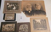 Seven antique black and white photos, visibly aged and worn, laid out for display including portraits and group shots.
