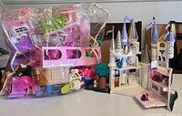 Photo showing the Beauty & The Beast castle with attached tree and multiple spires, next to a clear plastic bag containing various doll furniture and toys in different colors.