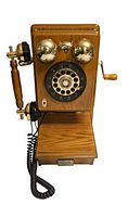 Front view of light oak wood box wall phone with rotary dial, brass bells, wooden handset, coiled cord, and crank handle on the side.