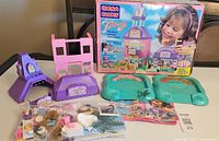 Overview of main components including pink and purple plastic castle parts, green bases, figures, and manual with box in background