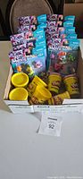 Box containing multiple unopened yellow Play-Doh containers and My Little Pony Movie character figures in sealed packaging.