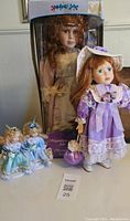 Set of four porcelain dolls with one in original box packaging showing overall lot contents
