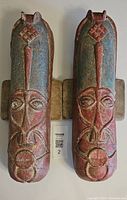 Front view of the pair of pottery masks mounted on wooden blocks, showing overall condition and design details.