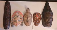 Five different wooden masks from Indonesia and Thailand displayed side by side, showing size, style, and condition variations.