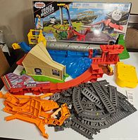 Photo showing the various plastic track components laid out next to the original box, including ramps and track pieces.