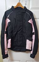 Front view of the women's motorcycle jacket showing black fabric with pink accents and zipper detailing.