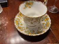 Royal Albert Marjorie teacup sitting inside matching saucer showing yellow floral pattern and gold rim