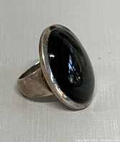 Front angled view of the sterling silver ring with large black onyx stone showing polished bezel setting and surface reflections.
