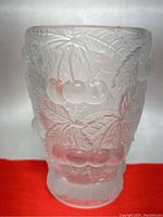 Frosted clear glass vase with raised cherry and leaf patterns photographed from an angle to show surface details.