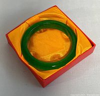Bright green jade bangle placed in red and yellow cushioned box