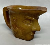 Photo of the jade face jug showing the left profile with carved facial features and handle.