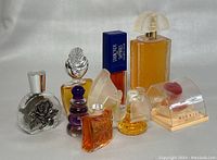 Overview image of the eight perfume bottles showing various shapes, colors and designs with amber and yellow liquid inside.
