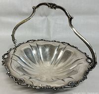 Front angled view showing scalloped edges, floral decorations, and the raised handle on the silver candy dish.