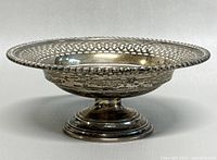 Front left angle view of footed bowl showing pierced gallery rim and pedestal base