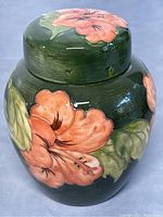 Front view of ginger jar and lid showing orange floral decoration on green ground