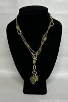 Full view of a 40-inch vintage necklace on a black display bust showing the green beads and silver-tone chain.