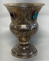 Front view of silver-plated footed cup showing engraved scrollwork and red/blue rhinestones